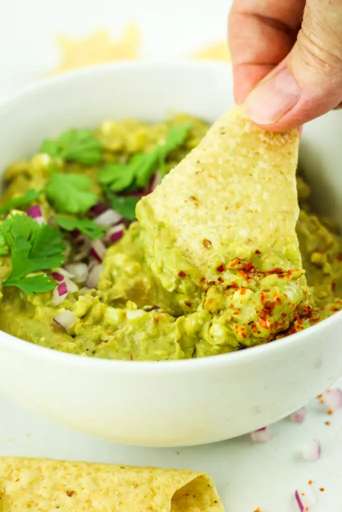 A bowl of cottage cheese guacamole with chips to enjoy this high protein dip.